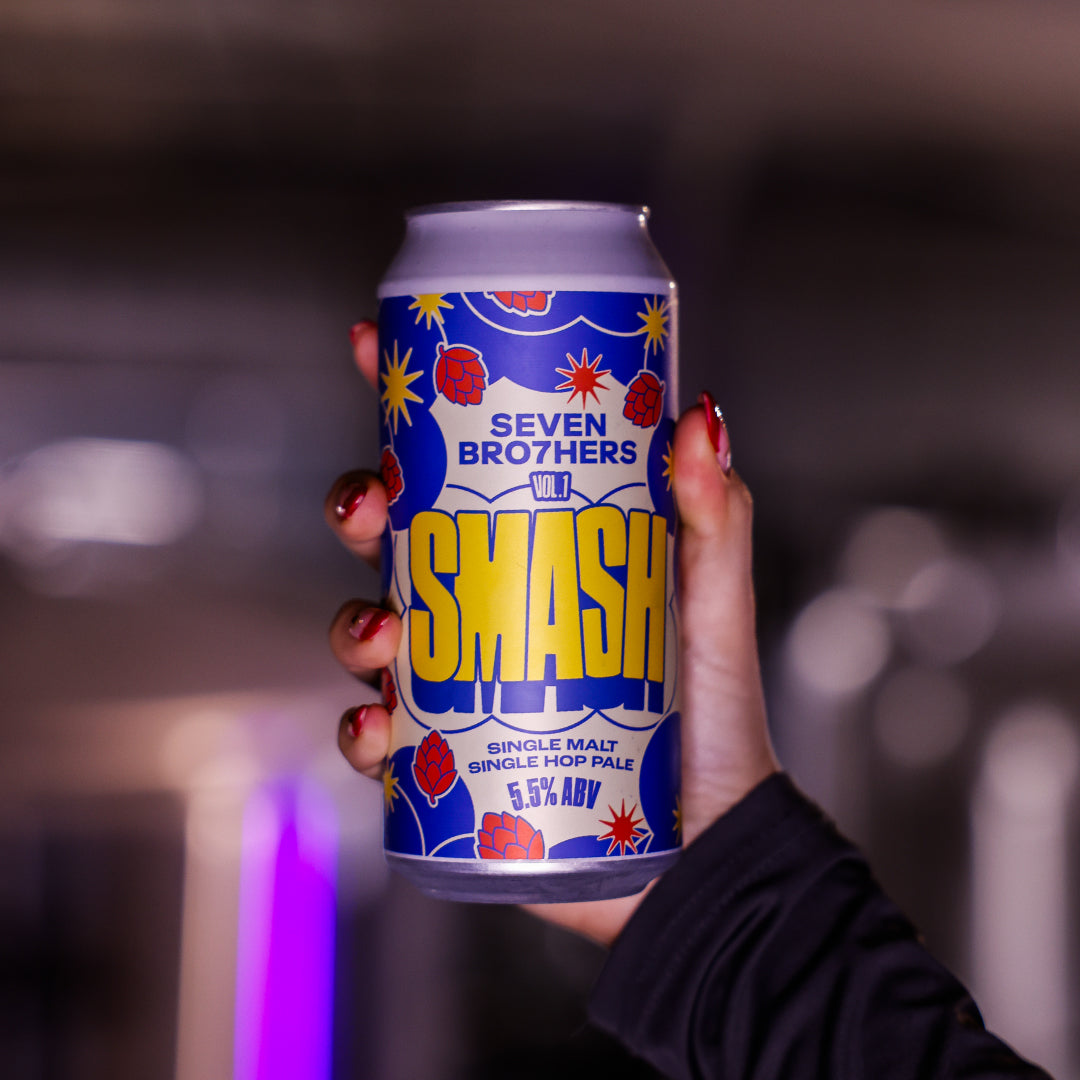 Hand holding a can of Seven Brothers Smash single malt single hop pale ale with a blurred background.